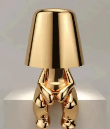 Gold thinker lamp seated with legs hanging