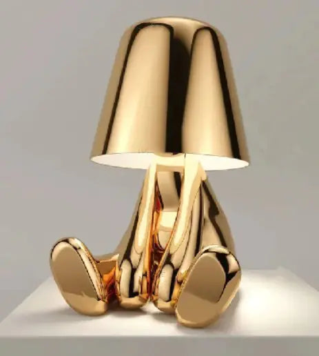 Gold thinker statue desk lamp seated with legs forward and soft light glow