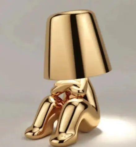 Gold thinker table lamp in relaxed seated position with legs bent