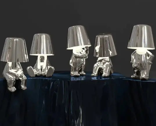 Group of silver and gold thinker lamps displayed on a black table
