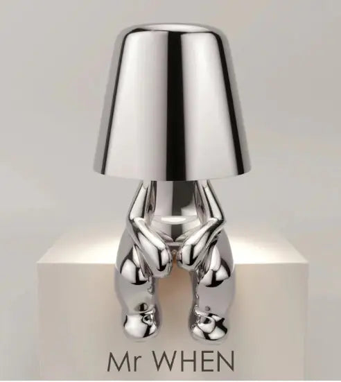 Silver thinker lamp seated with legs extended and clean white background