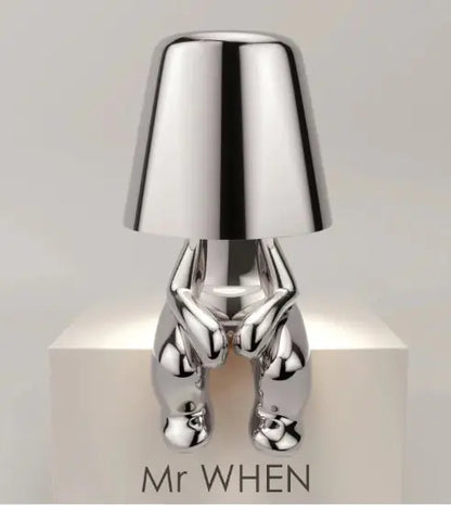 Silver thinker lamp seated with legs extended and clean white background